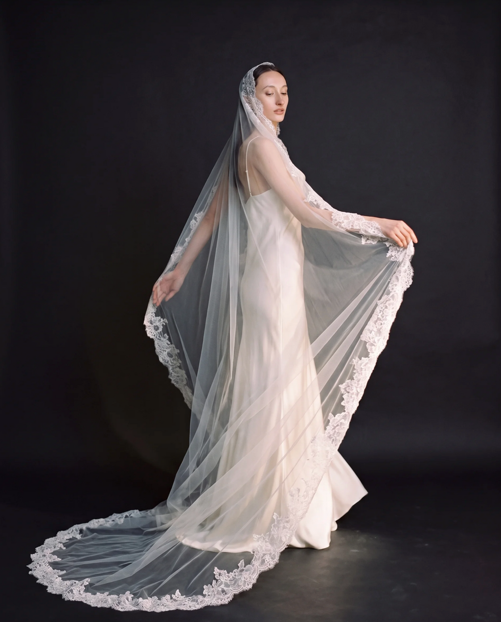 The Valentina veil — bride holding out the lace-edged veil
