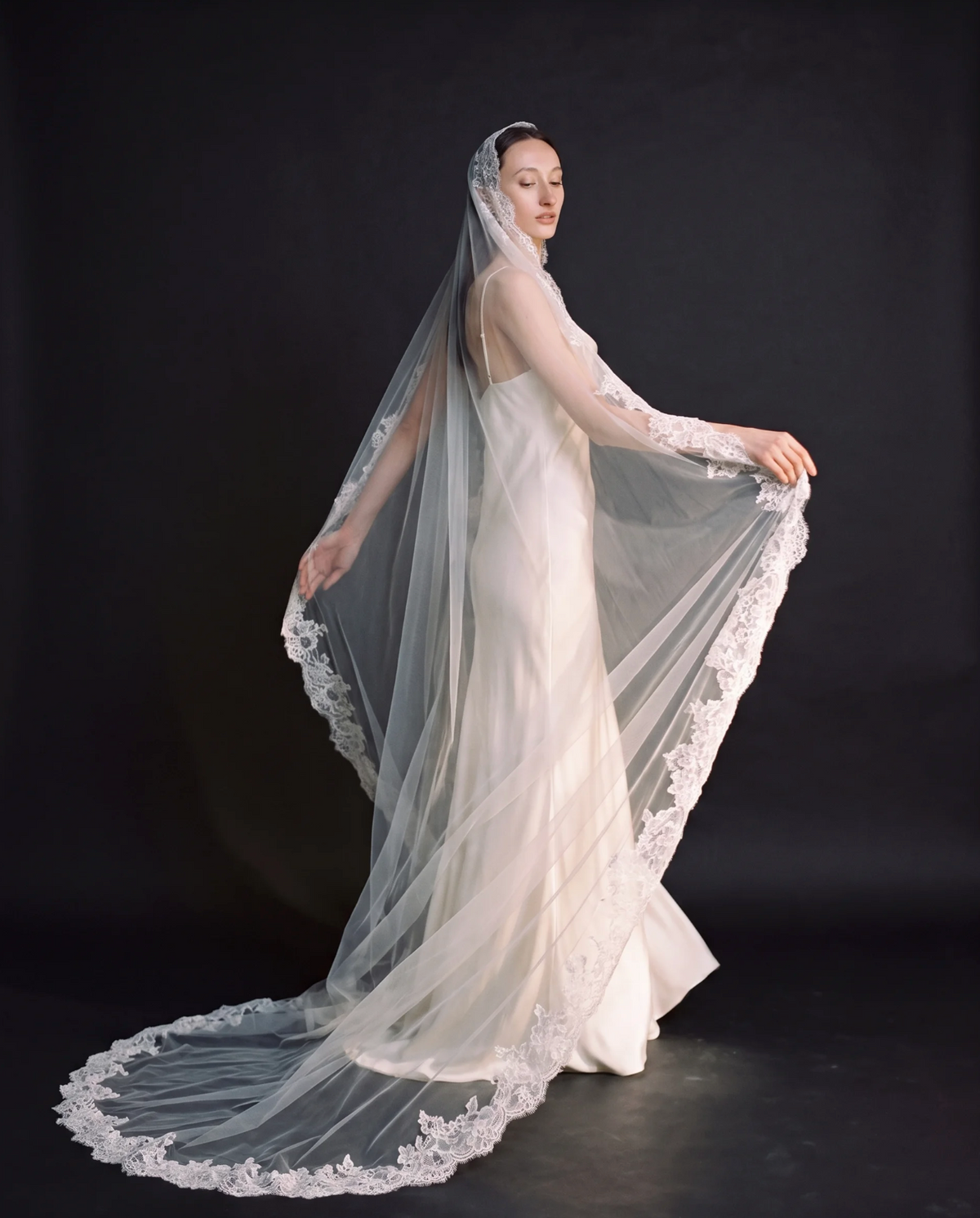The Valentina veil — bride holding out the lace-edged veil