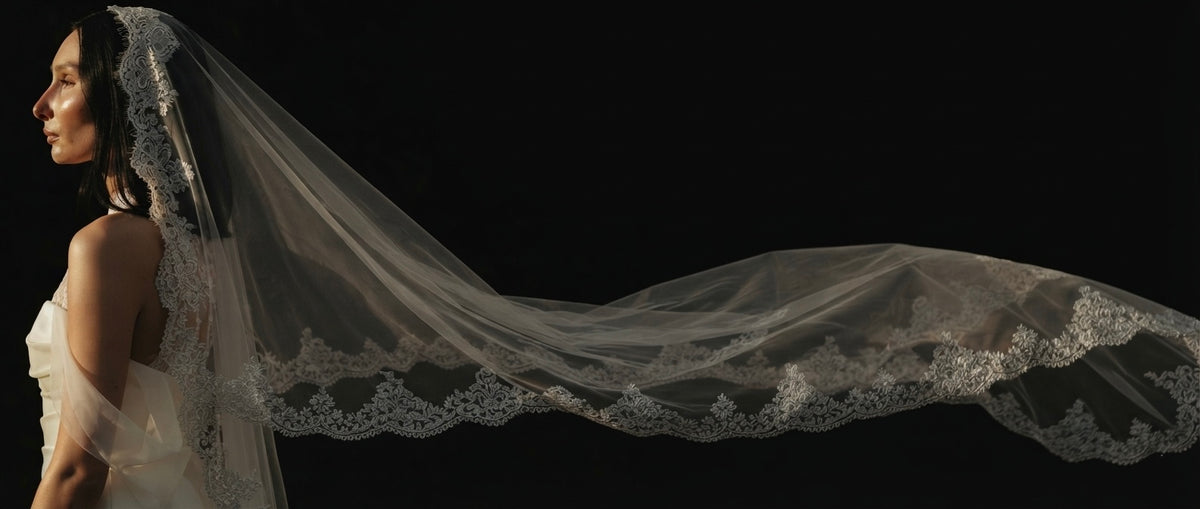 Bride in a long lace-edged veil flowing in a field