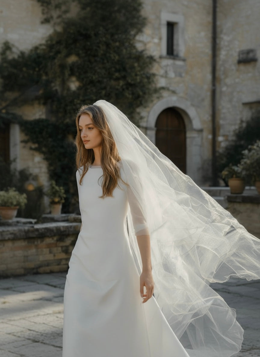 Bride in a long tulle veil in a stone courtyard