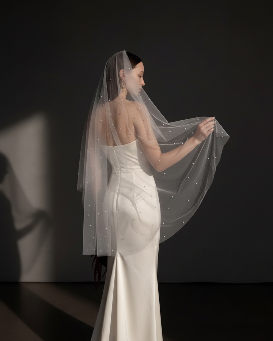 The Celeste veil — bride lifting the pearl tulle veil