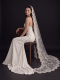 The Ysabel veil — bride seated with the floral lace border on the floor