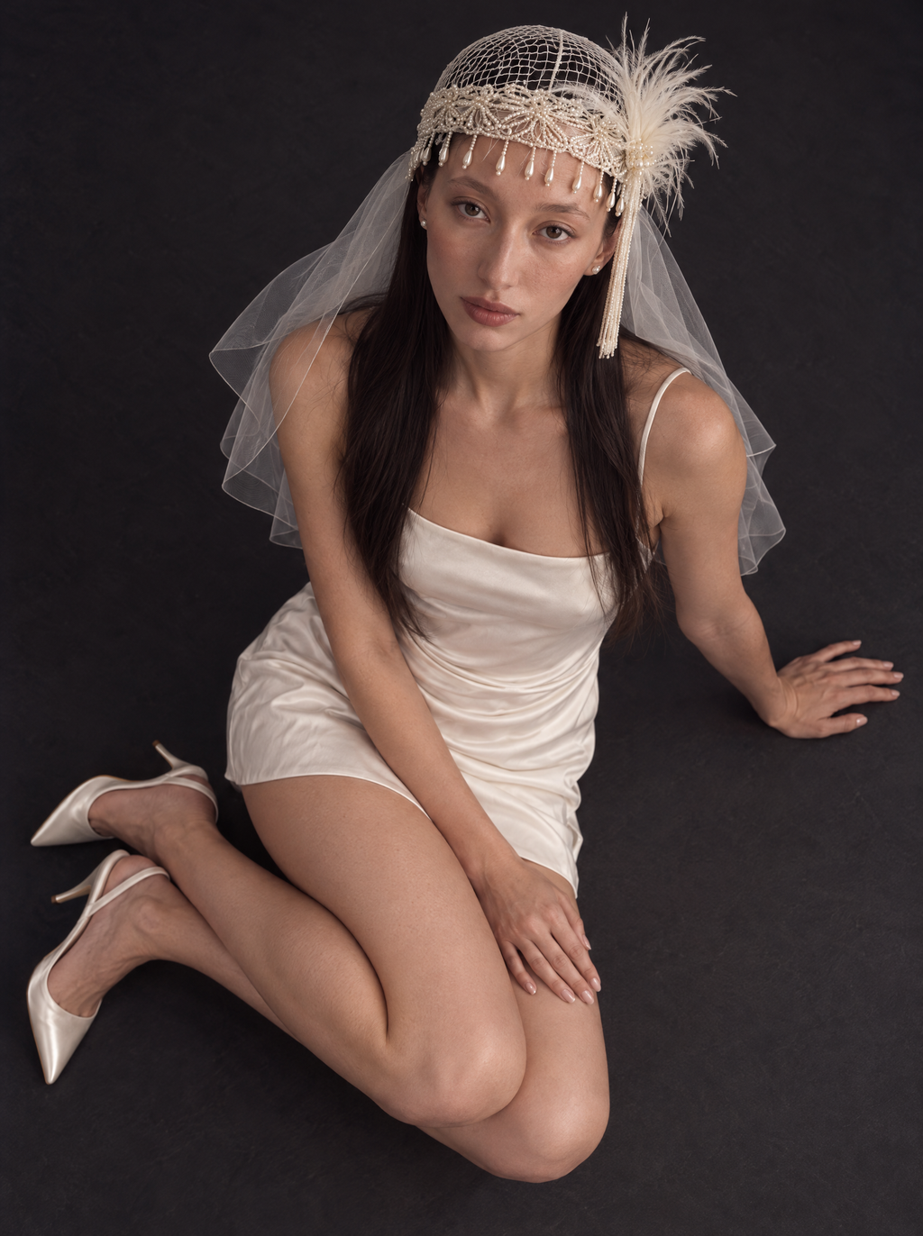 The Isolde veil — bride seated on the floor in the beaded cap and shoulder veil